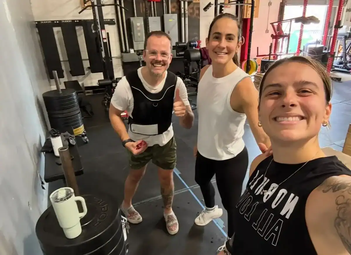 Three Wodify athletes smiling after a workout in a gym.