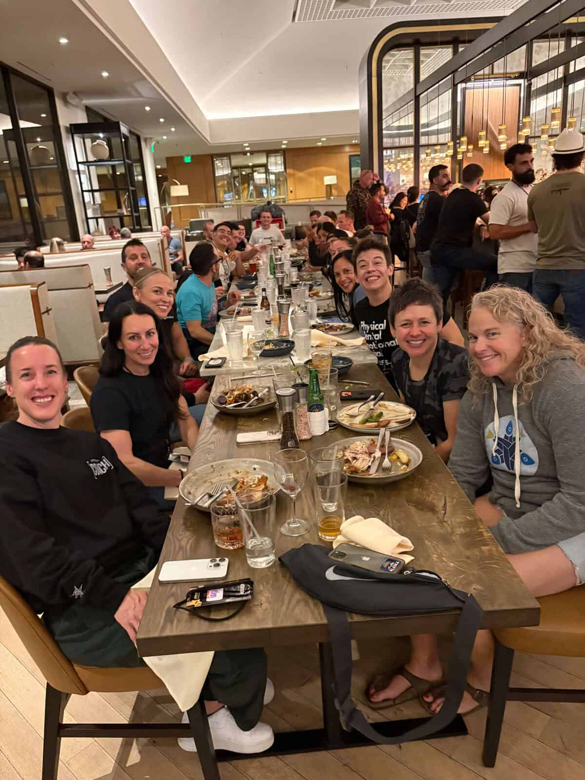 Wodify team members smiling and enjoying a meal together at a long restaurant table.