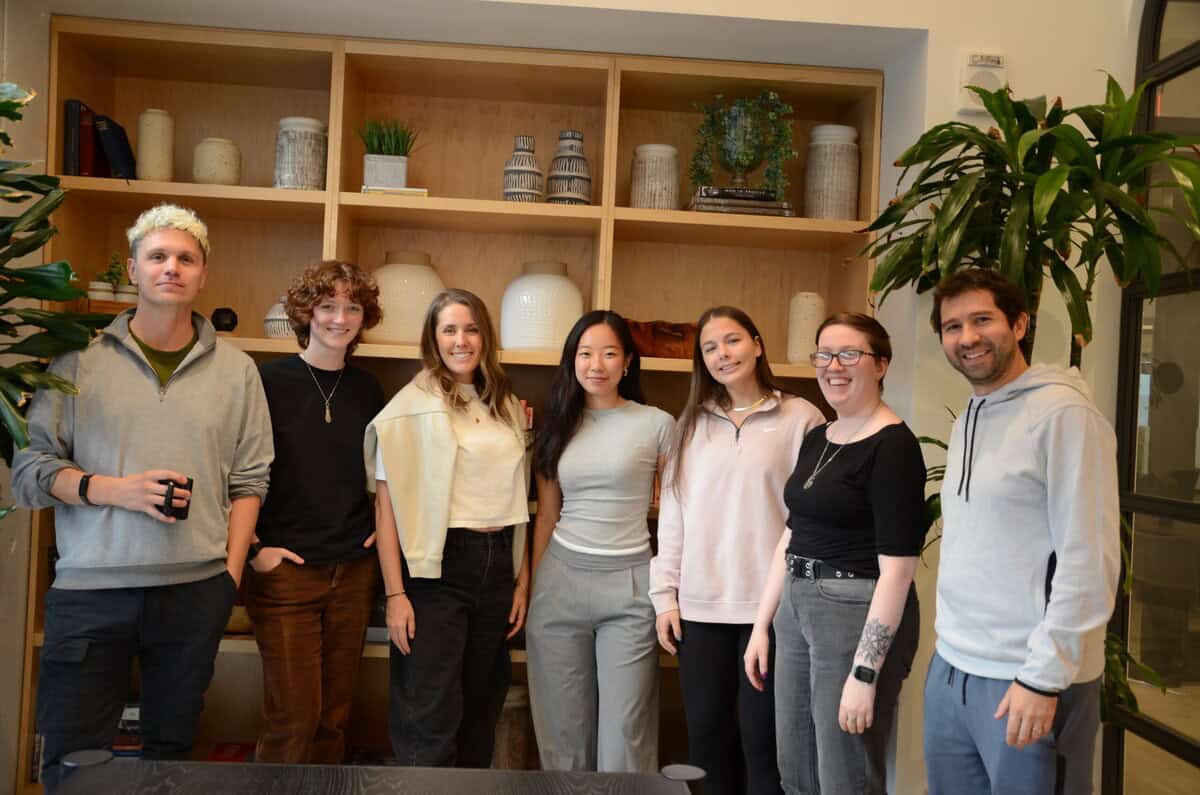 Wodify team members stand smiling in an office with shelves and plants.