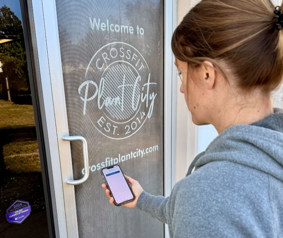 A person uses the Wodify app on a phone to check into a CrossFit gym.